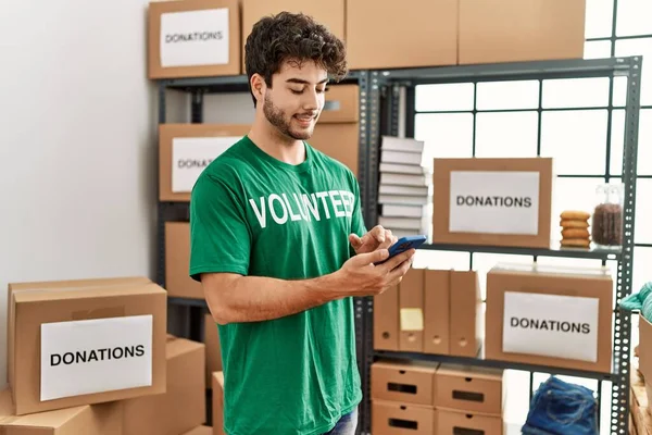 Jonge Spaanse Man Vrijwilligersuniform Met Smartphone Een Liefdadigheidscentrum — Stockfoto