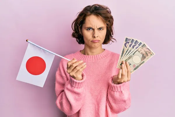 拿着日本国旗和日元钞票的年轻的黑发女人忧心忡忡 愤怒地哭泣着 害怕着 悲伤的表情 — 图库照片