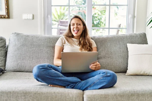 Linda Jovem Morena Sentada Sofá Usando Laptop Casa Colando Língua — Fotografia de Stock