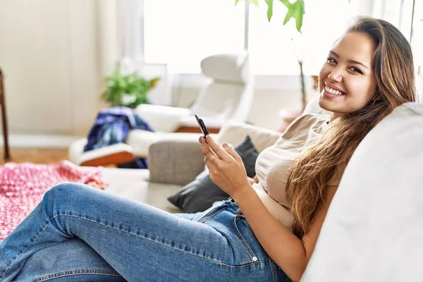 Jovem Hispânica Usando Smartphone Sentado Sofá Casa — Fotografia de Stock