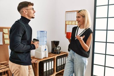 İki iş adamı gülümsüyor, ofiste kahve içiyorlar..