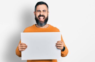 Sakallı, boş pankart taşıyan İspanyol bir adam komik bir ifadeyle dilini dışarı çıkarıyor.. 