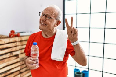 Spor kıyafetleri ve havlu giyen son sınıf öğrencisi kameraya bakıp zafer işareti yaparken gülümsüyor. İki numara.. 