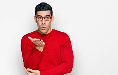 Yakışıklı İspanyol bir adam, günlük kıyafetler ve gözlük takıyor kameraya bakıyor ve havada bir öpücük savuruyor. Güzel ve seksi. aşk ifadesi. 