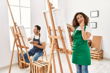 İspanyol orta yaşlı bir kadın ve sanat stüdyosunda olgun bir adam. Ciddi bir yüz ifadesi. Çene ve çene üzerine soru sormayı düşünüyorlar. 