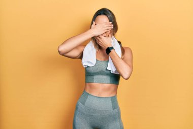 Güzel İspanyol kadın spor giyer ve havluyla gözlerini ve ağzını kapar, şaşırır ve şok olur. duygu gizleme 