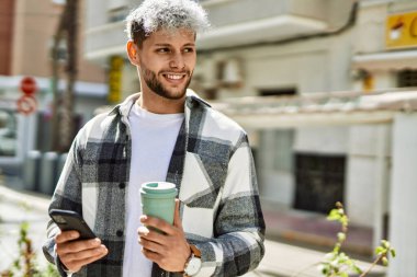 Genç İspanyol adam akıllı telefon kullanıyor. Şehirde kahve içiyor..