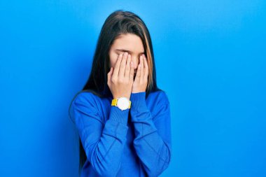 Balıkçı yaka kazak giyen genç esmer kız yorgunluk ve baş ağrısı için gözlerini ovalıyor, uykulu ve yorgun bir ifade takınıyor. görme sorunu 