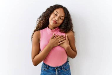 Güzel İspanyol kadın soyutlanmış arka planda duruyor elleri göğsünde, gözleri kapalı ve yüzünde minnet dolu bir jest ile gülümsüyor. sağlık kavramı. 