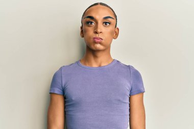 Makyaj yapan, uzun saçlı, sıradan tişörtlü, komik yüzlü İspanyol bir adam. Havayla şişmiş ağız, çılgın bir ifade.. 