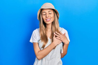 Kaşif şapkası takan güzel İspanyol kadın elleri göğsünde, gözleri kapalı ve yüzünde minnet dolu bir jest ile gülümsüyor. sağlık kavramı. 