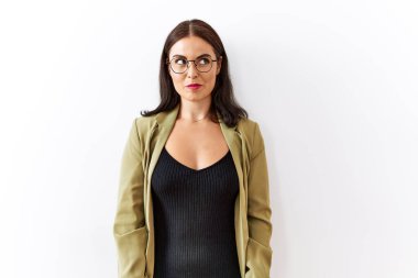 Genç esmer kadın izole edilmiş arka planda duruyor. Gülümsüyor, yan tarafa bakıyor ve düşünüyor.. 