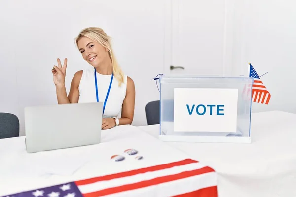 アメリカの政治運動の選挙で若い白人女性が勝利のサインをしている指を示すカメラを見て微笑んだ — ストック写真