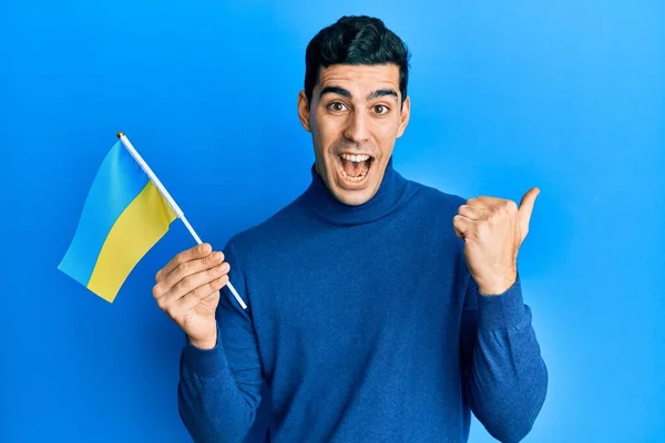 Bonito Hispânico Vestindo Bandeira Ucraniana Apontando Polegar Para Lado Sorrindo — Fotografia de Stock