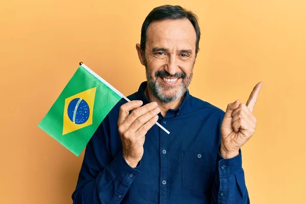 Středověký Hispánec Drží Brazilskou Vlajku Šťastně Úsměvem Ukazuje Rukou Prstem — Stock fotografie