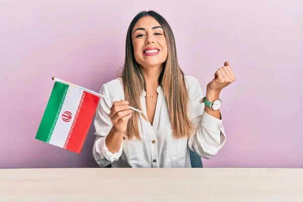 Jovem Hispânica Segurando Bandeira Irã Sentada Mesa Gritando Orgulhoso Celebrando — Fotografia de Stock