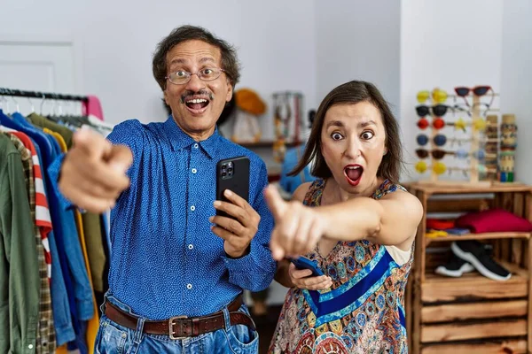 Middle Age Interracial Couple Retail Shop Using Smartphone Pointing Finger — Stock Photo, Image