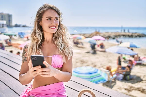 Mladá Blondýna Dívka Pomocí Smartphone Sedí Lavičce Pláži — Stock fotografie