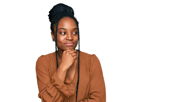 年轻的非洲裔美国女人穿着休闲装 双手托着下巴思考着问题 沉思着自己的表情 脸上挂着沉思的笑容 怀疑概念 — 图库照片