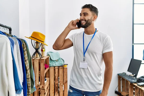 年轻的阿拉伯男子店主在服装店的衣架旁用智能手机交谈 — 图库照片