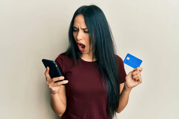 Ung Latinamerikansk Flicka Håller Smartphone Och Kreditkort Arg Och Galen — Stockfoto