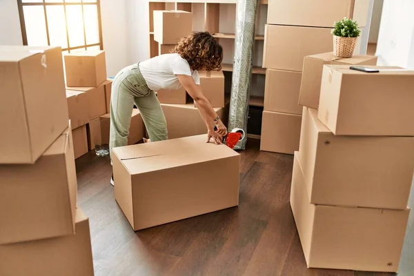 Orta yaşlı İspanyol kadın yeni evinde karton kutu paketlerken kendine güler.