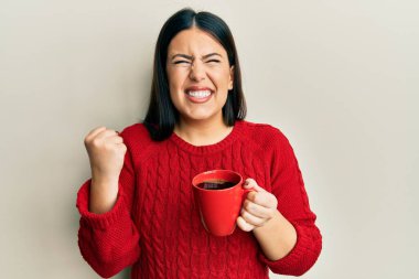 Güzel esmer kadın bir fincan sade kahve içiyor gururla bağırıyor, zaferi kutluyor ve başarıyı kollarını kaldırarak kutluyor. 