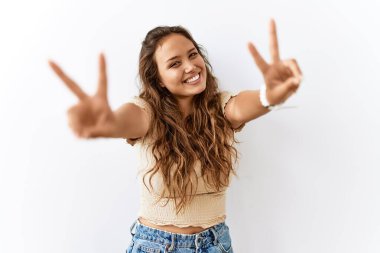 Güzel İspanyol kadın arka planda dikilip kameraya bakıp zafer işareti yaparken gülümsüyor. İki numara.. 