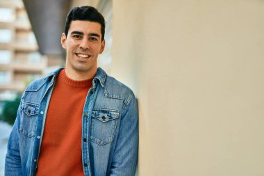 Genç İspanyol adam gülümseyerek şehirde mutlu mesut dikiliyor..