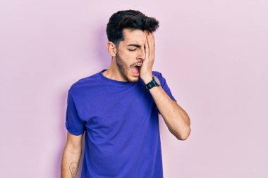 Gündelik tişört giyen İspanyol genç adam esneyerek yorgun yüzünü, gözünü ve ağzını eliyle kapatıyor. Yüzüm acıyor.. 