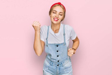 Gündelik giysiler giyen genç beyaz kız kolları havada ve gözleri kapalı bir şekilde başarıyı kutluyor ve şaşırıyor. Kazanan konsept. 