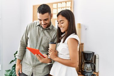 İki Latin iş adamı ofiste kahve içerek dokunmatik ped kullanıyor..