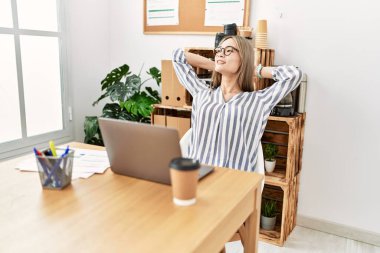 Genç Çinli kadın gülümsüyor. Kendine güveni tam. Ofiste elleri rahat.