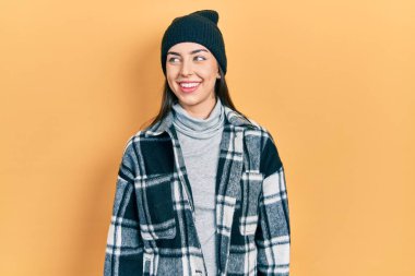 Mavi gözlü, yünlü şapka takan güzel bir kadın, rahat bir görünüm ve kendine güvenen bir gülümsemeyle poz veriyor.. 