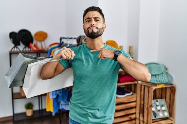 Satış mağazasında sakallı, alışveriş torbaları tutan, boğazını bıçak niyetine kesen genç yakışıklı bir adam, saldırganlığı şiddetle tehdit ediyor. 