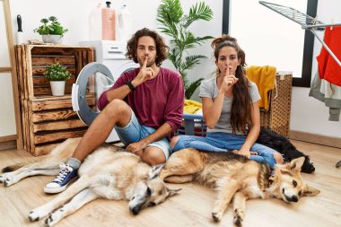 Genç İspanyol çift, köpeklerle çamaşır yıkıyor ve parmakları dudaklarında sessiz olmak istiyorlar. sessizlik ve gizli konsept. 