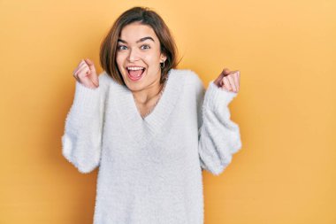 Gündelik giysiler giyen genç beyaz kız kollarını kaldırarak ve gözlerini açarak başarının şokunu yaşıyor. Kazanan konsept. 