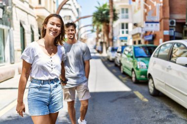 Genç İspanyol çift gülümsüyor. Mutlu bir şekilde el ele tutuşuyorlar..