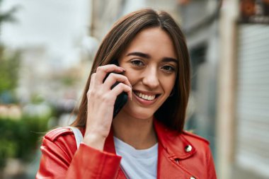 Genç İspanyol kadın gülümsüyor. Şehirdeki akıllı telefondan konuşuyor..