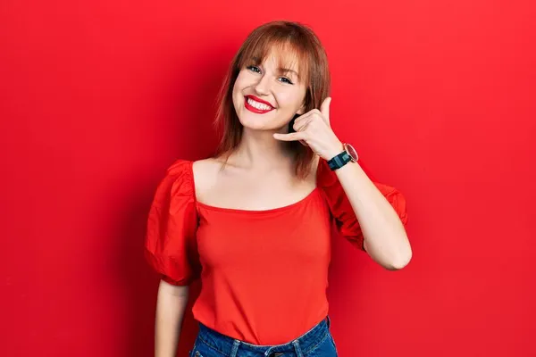 Rudowłosa Młoda Kobieta Czerwonej Koszuli Uśmiechająca Się Robiąca Gest Telefoniczny — Zdjęcie stockowe