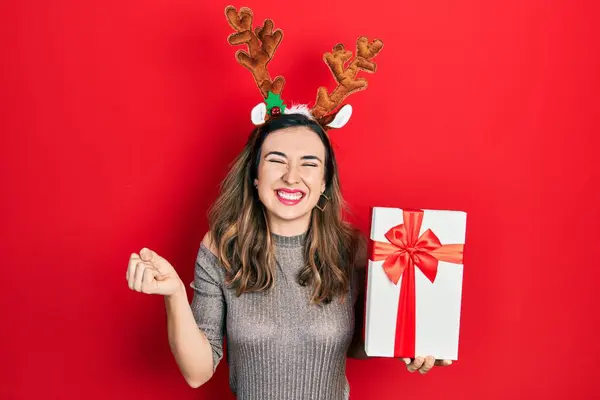 Mladý Hispánec Dívka Nosí Jelena Vánoční Klobouk Drží Dárek Křičí — Stock fotografie