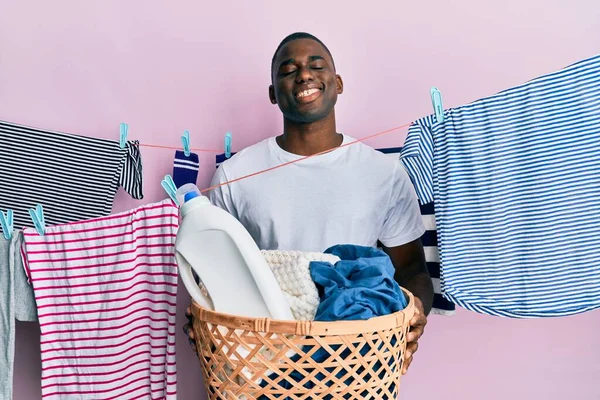 年轻的非洲裔美国人拿着洗衣篮 脸上挂着快乐而凉爽的笑容 显示牙齿 — 图库照片
