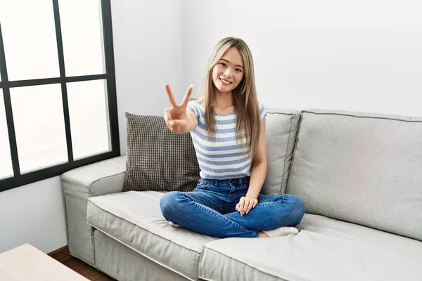 Mujer Joven Asiática Sentada Sofá Casa Sonriendo Mirando Cámara Mostrando —  Fotos de Stock