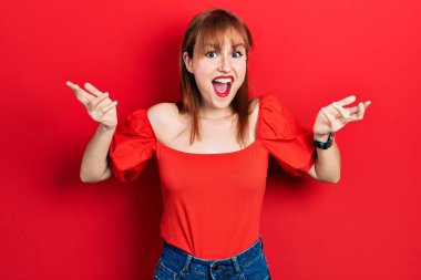 Kırmızı tişörtlü genç bir kadın çılgınlığı kutluyor ve başarıya hayran kalıyor kolları açık ve gözleri açık heyecanla bağırıyor. Kazanan konsept 