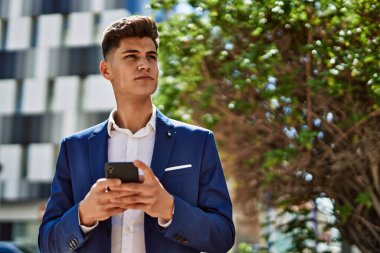 Genç adam parkta akıllı telefon kullanıyor.