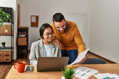 Ofiste masa başında çalışırken gülümseyen iki iş adamı..