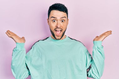 Gündelik kıyafetler giyen genç İspanyol adam zaferi mutlu bir gülümsemeyle ve kazanan yüz ifadesiyle kutluyor. 