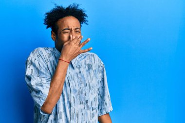 Sakallı, sıradan giyinmiş, pis ve iğrenç bir koku alan, nefesini burnunda tutan Afro-Amerikalı genç bir adam. Kötü kokuyor. 