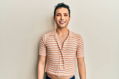 Makyaj yapan yakışıklı, sıradan bir tişört giyen, yüzünde mutlu ve havalı bir gülümseme olan bir adam. şanslı kişi. 