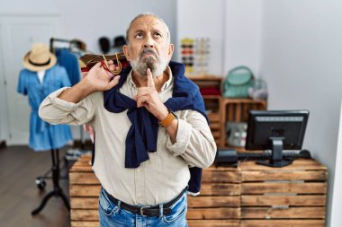 Butik dükkanında alışveriş torbaları tutan yakışıklı bir adam. Düşünceleri kuşkuya odaklanmış, çenesinde parmak olan ve kafasını kaldırıp, 